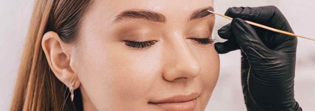 a woman is getting her eyebrows done by a professional makeup artist
