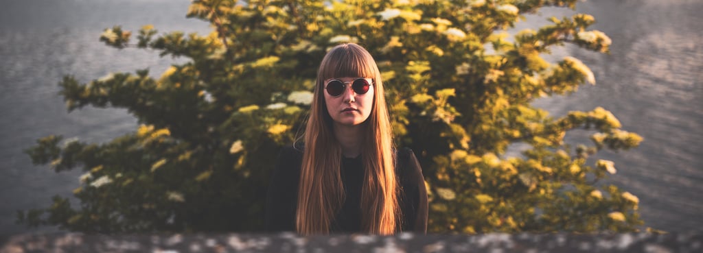 a woman with long hair and sunglasses in front of a brush