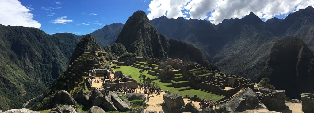 Panorama du Machu Picchu sous un ciel bleu éclatant, les terrasses incas et les ruines baignées de l