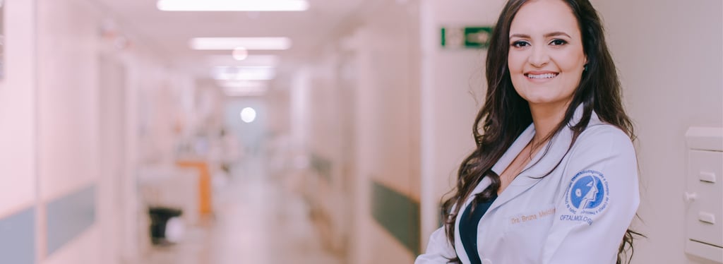 Dra Bruna Melchior de jaleco branco sorrindo de braços cruzados, aos fundos um corredor do hospital das clinicas da USP