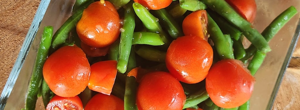 a bowl of green beans and tomatoes on a wooden table