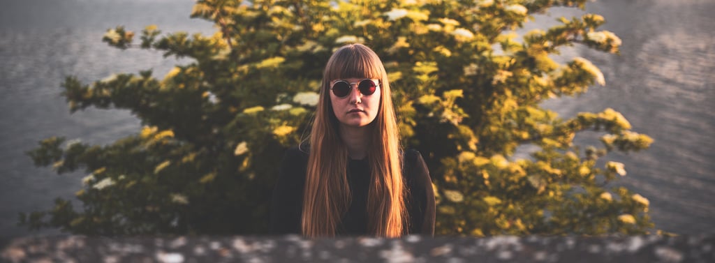 a woman with long hair and sunglasses in front of a brush