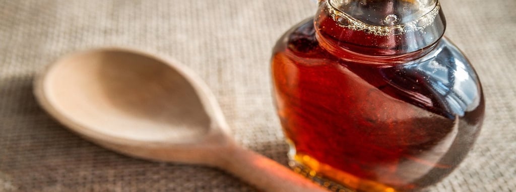 Maple syrup in a glass bottle and a wooden spatula