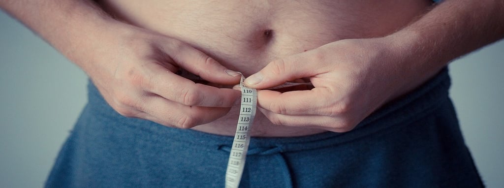 Person holding measuring tape around his stomach