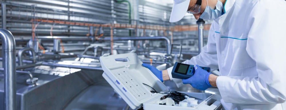 a man in a white lab coat and gloves is holding a laptop computer