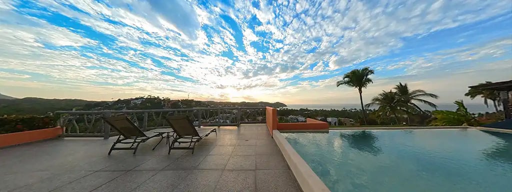 a pool with lounge chairs and a view of the ocean