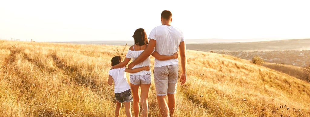 Happy family of three walking outdoors, enjoying nature together.