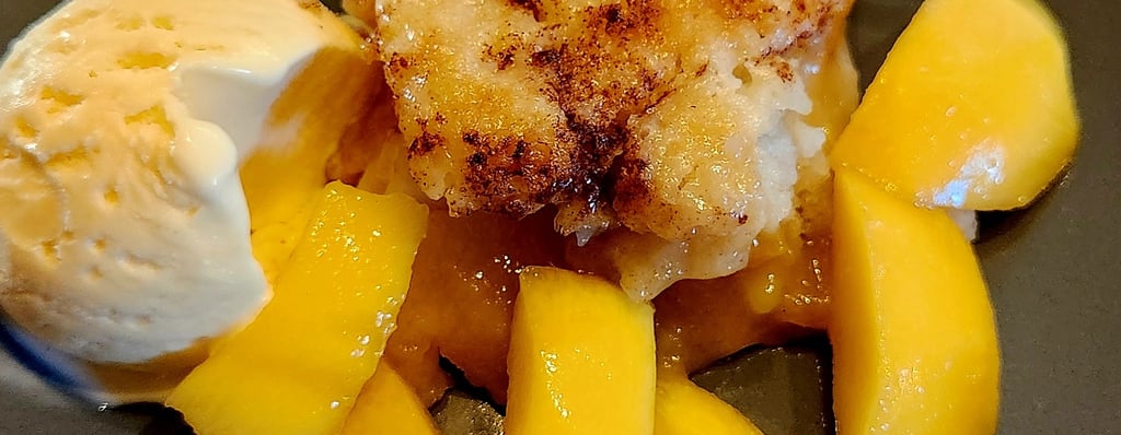 a peach cobbler dessert with a scoop of ice cream and a fork