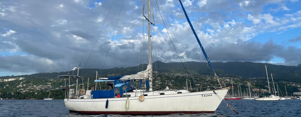 Sailboat Tauha behind the reef in crystal-clear waters near Tahiti, French Polynesia