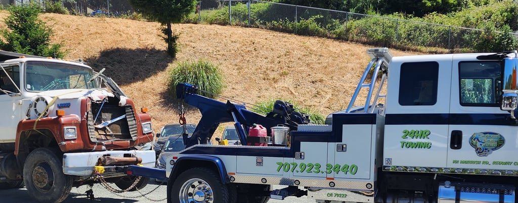 Redwood Towing medium duty tow truck towing a large dump truck.