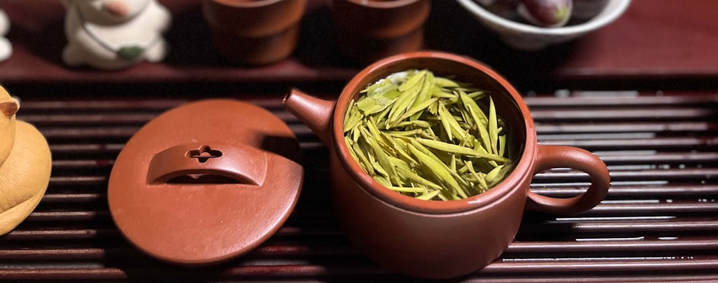 Tea set placed on a wooden tea tray, with green tea inside the teapot