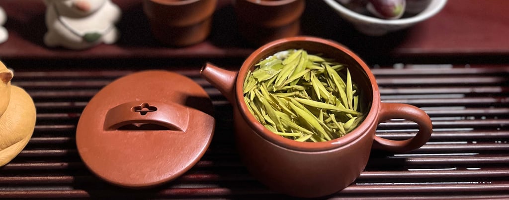 Tea set placed on a wooden tea tray, with green tea inside the teapot