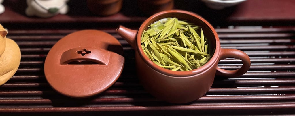 teapot and lid placed on a wooden tea table, with tea leaves inside the pot