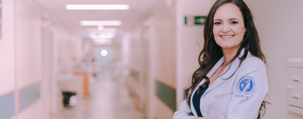 Dra Bruna Melchior de jaleco branco sorrindo de braços cruzados, aos fundos um corredor do hospital das clinicas da USP