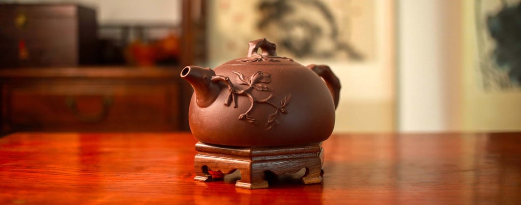 Teapot with an embossed design placed on a wooden stand