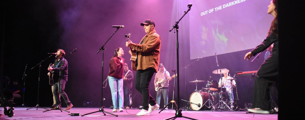 A band leading worship on stage, with guitars, drums, and singers