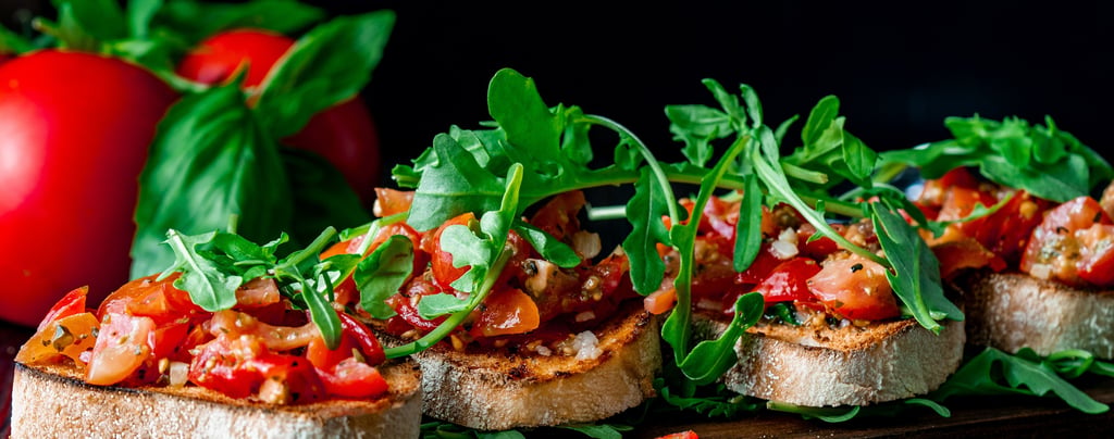 Frische Tomaten-Basilikum-Bruschetta auf geröstetem Baguette mit Rucola.