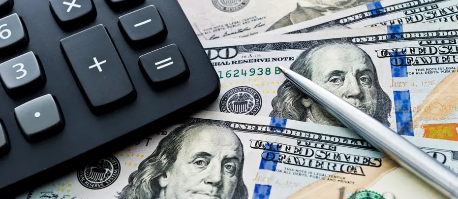 alt="Calculator and pen on top of hundred dollar bills representing business loan brokering and funding support"