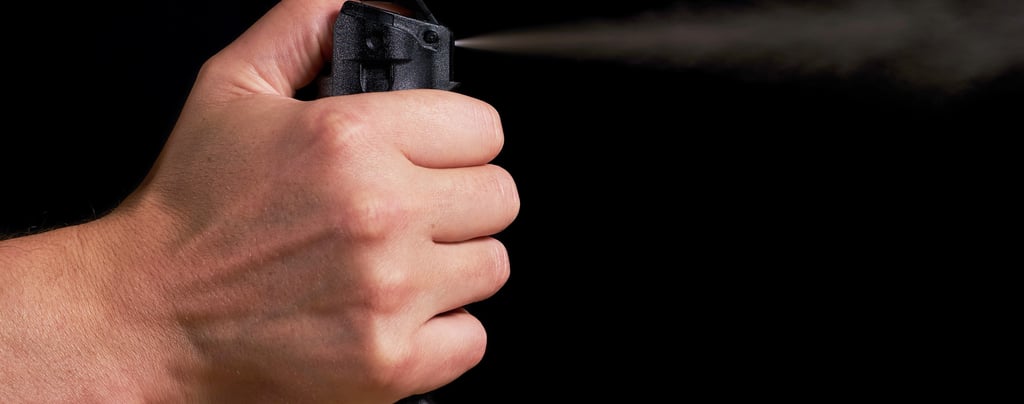 a person holding pepper spray non lethal weapon