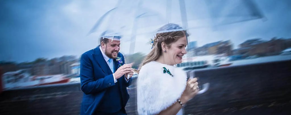 wedding couple with umbrellas running from the rain
