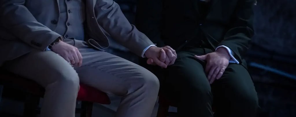 two grooms sitting holding hands
