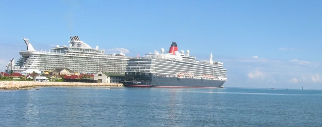 Navios de cruzeiro Oasis of the Seas e Queen Elizabeth ancorados em Falmouth, Jamaica, mostrando o porto e a costa tropical
