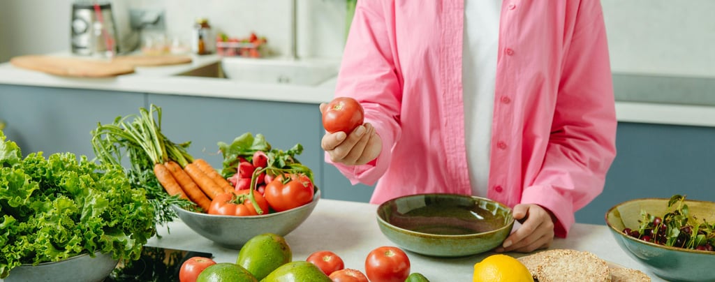 person holding a tomato while having vegetables on the kitchen counter 