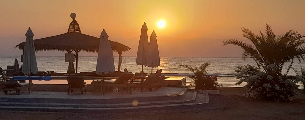 ein Sonnenaufgang an einem Strand mit Sonnenschirmen