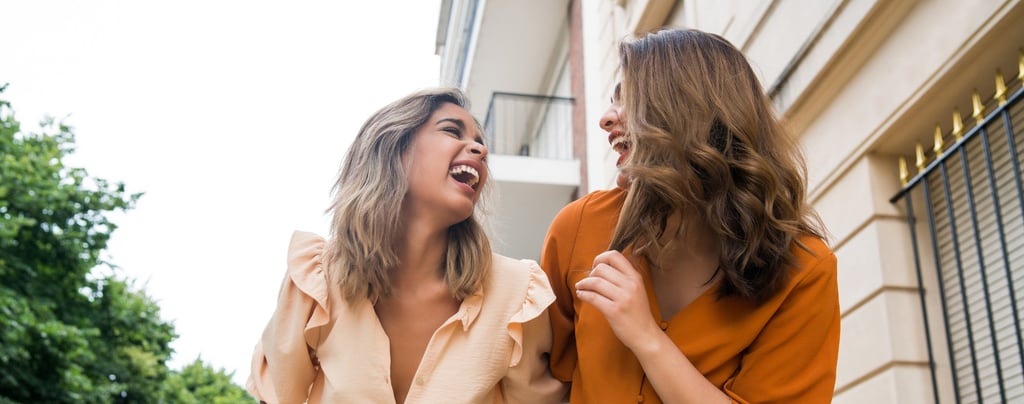 Dos hermanas adultas riendo y abrazadas, felices con su canción personalizada de Musycol.