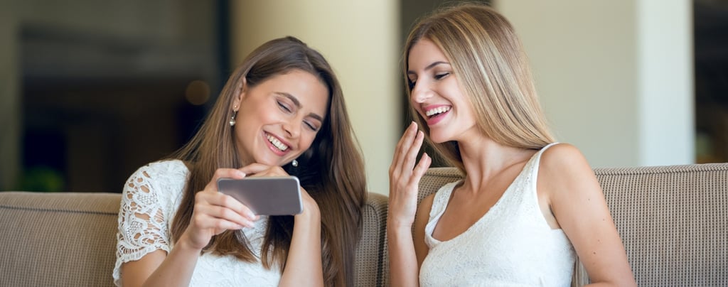 Dos amigas riendo mientras escuchan una canción personalizada de Musycol.