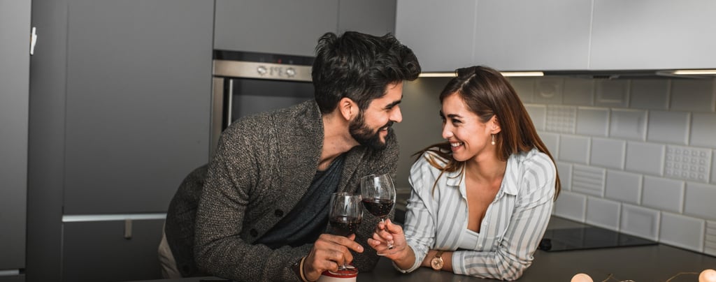 Pareja feliz celebrando su aniversario con una copa de vino escuchando una canción personalizada de Musycol.
