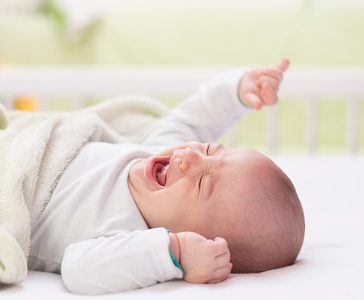a baby is crying and crying while laying on a bed
