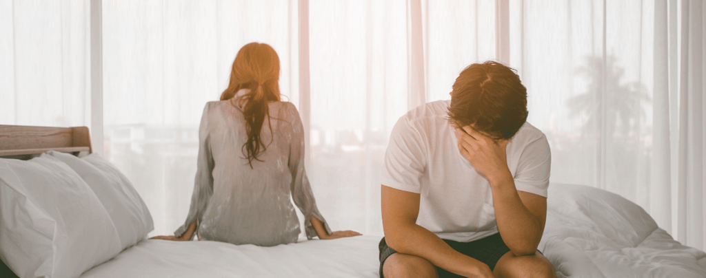 a man and woman sitting on a bed stressfully
