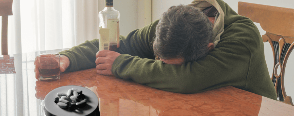 A man sitting at a table with a bottle of alcohol