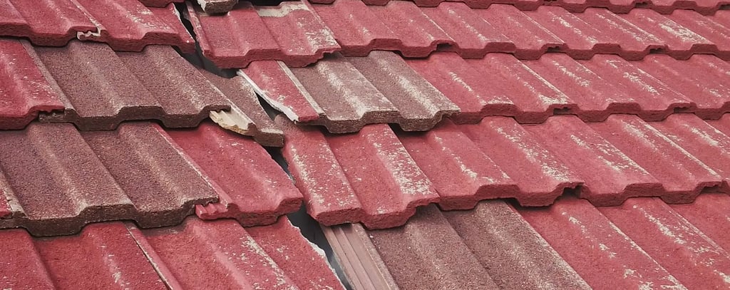 Cracked and missing roof tiles exposing underlay