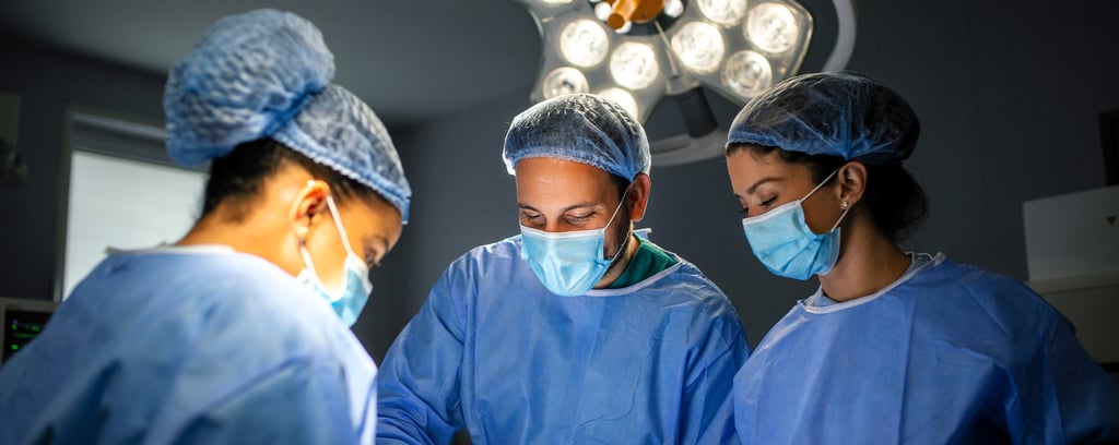 Three surgeons in blue scrubs and masks are focused on  operation in operating room.