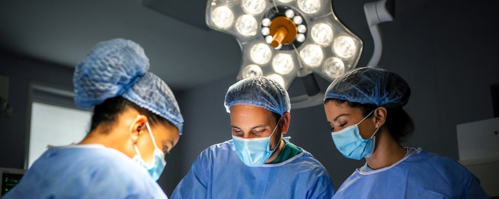 Three surgeons in blue scrubs and masks are focused on  operation in operating room.