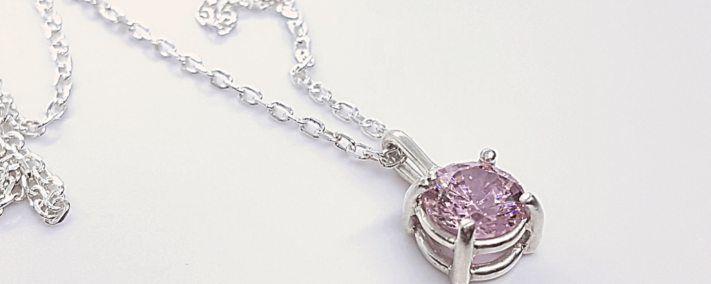 a necklace with a pink crystal pendant on a chain