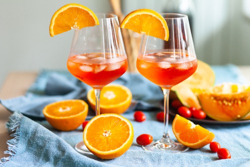two glasses of aperol spritz with oranges and cranberries