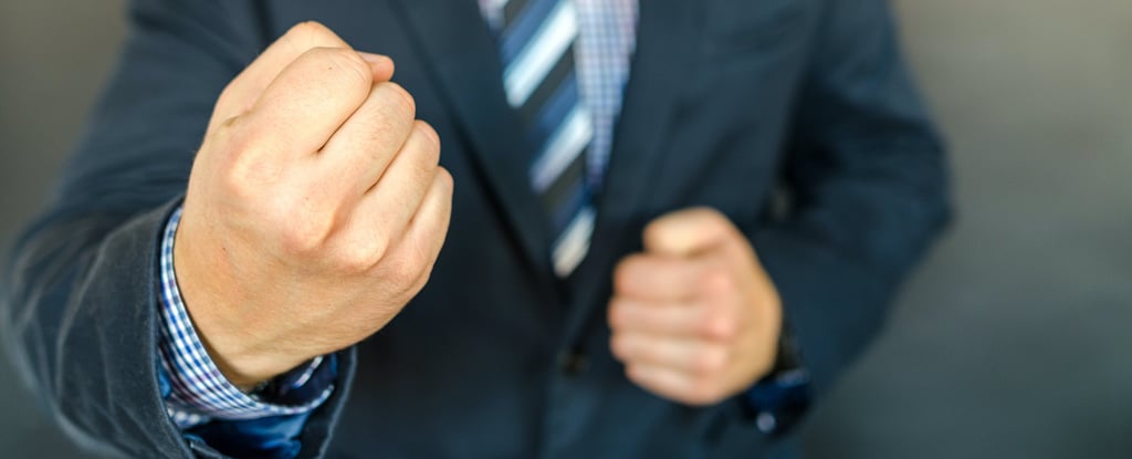 A man in a suit clinching his fists.