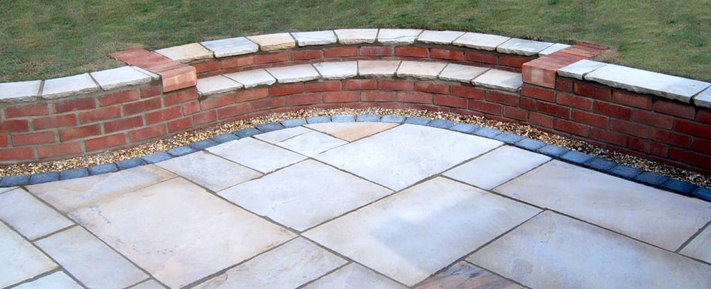Multi-level sunken sandstone patio step up to lawn with retaining wall