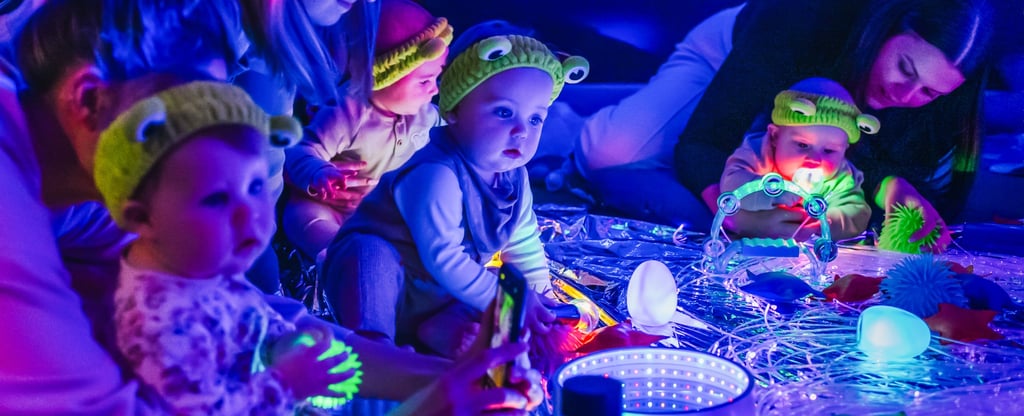 Babies in baby moo playing with the lights turned off and glow up instruments for space week,