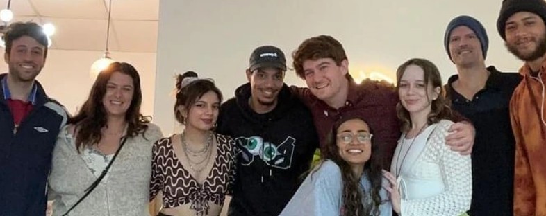 A diverse group of smiling young friends posing together for a group photo indoors.