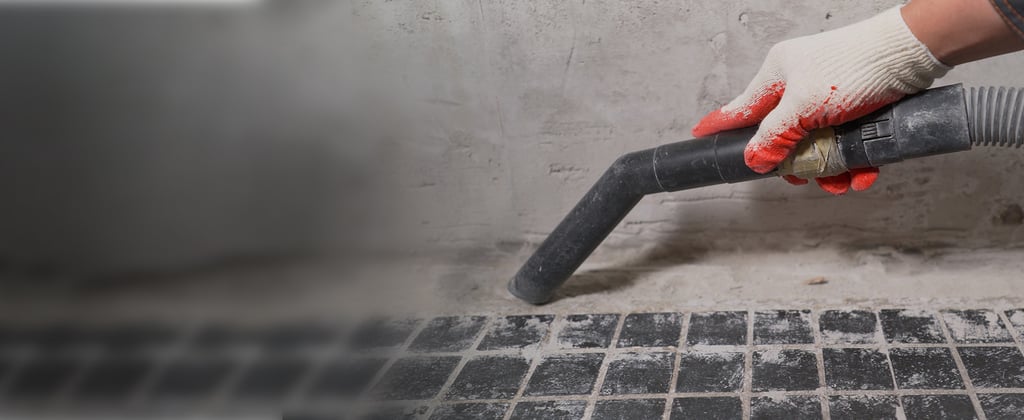 Mão a operar um aspirador durante a limpeza pós-obra, evidenciando a remoção de detritos