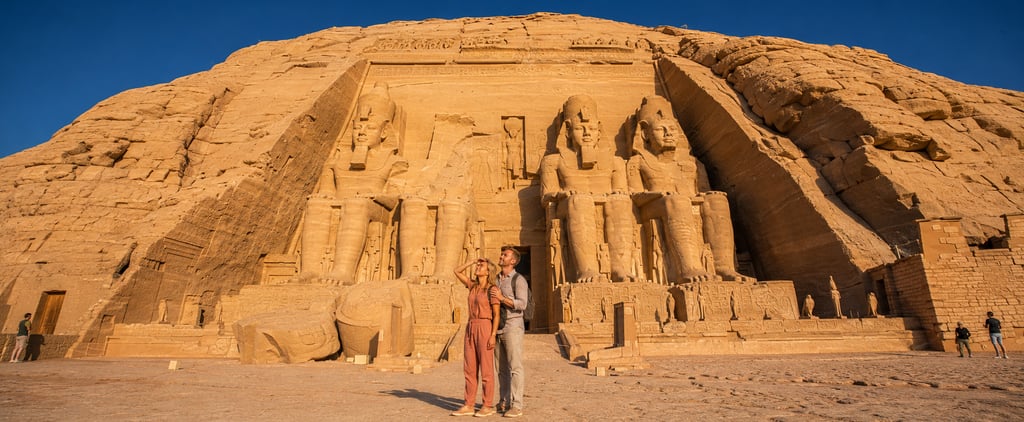 Couple admiring the colossal statues of Ramses II at the historic Abu Simbel Temple in Egypt.