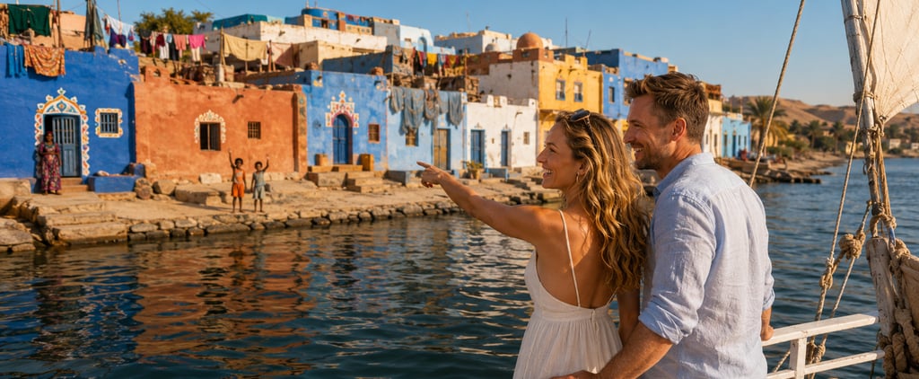A smiling couple on a boat looks at the colorful Nubian village houses along the Nile River in Egypt.