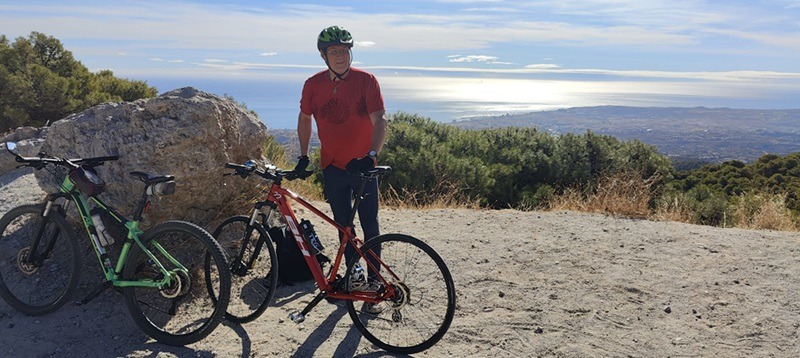 a man standing  with green and red mountain bikes on top of the mountain