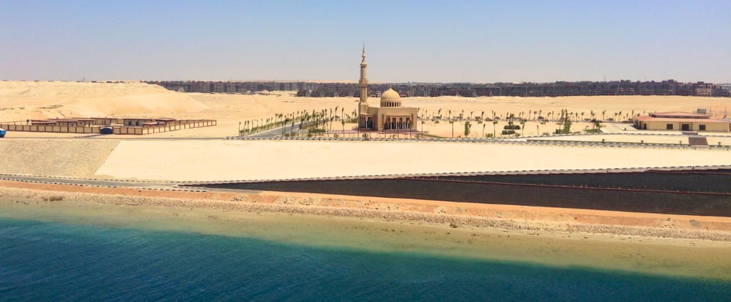 Vista da mesquita com deserto e areia contrastando com o mar ao fundo