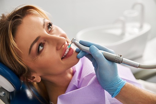A patient receives a professional dental cleaning and tooth polishing at a dentist office.