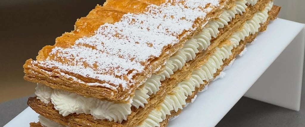 Gourmet mille-feuille pastry with layers of flaky puff pastry, whipped cream, and a fresh raspberry.